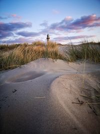 Road leading towards lighthouse on field against sky