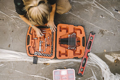 High angle view of woman with toolbox over concrete land