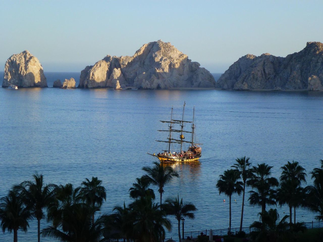 water, nautical vessel, mountain, sea, transportation, boat, tranquil scene, mode of transport, tranquility, beauty in nature, scenics, nature, moored, clear sky, mountain range, sky, tree, travel, idyllic, palm tree