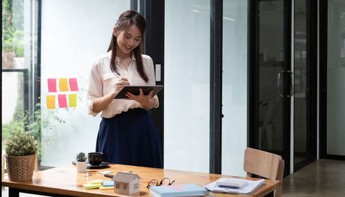 Side view of young woman using digital tablet while sitting on table