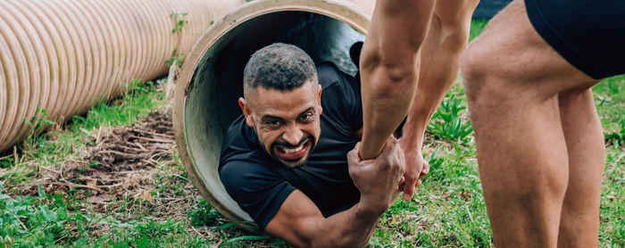 Man helping friend in coming out of pipe