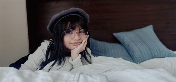 Portrait of young woman sitting on bed at home