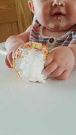 Midsection of baby with ice cream sitting on high chair at home