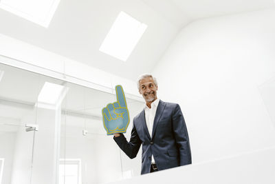 Smiling mature businessman holding toy hand in office