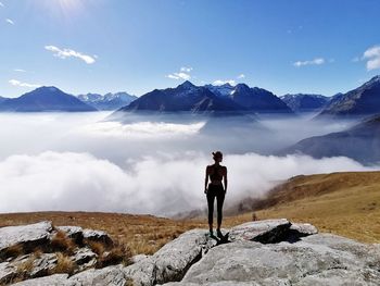 Rear view of man standing on rocks against mountain