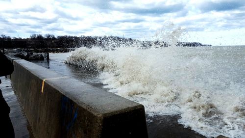 Water splashing on shore against sky