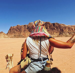 Midsection of person in desert against clear sky