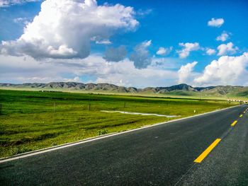 Empty country road against cloudy sky