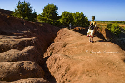 Rear view of people on rock against sky