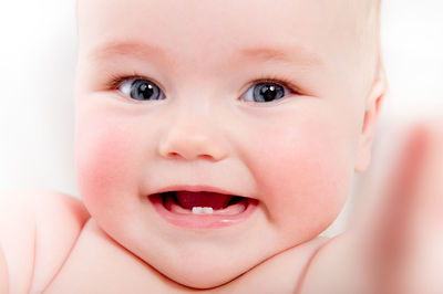 Close-up portrait of cheerful cute baby girl lying on bed