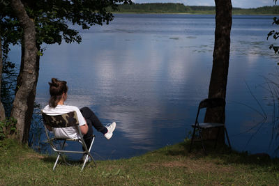 Women sitting on chair by lake