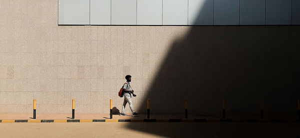 Wide shot of a man passing by towards the shadow area in an urban setting