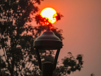 Low angle view of illuminated street light against orange sky