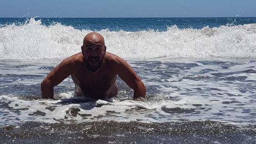 Portrait of shirtless man in sea