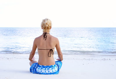 Rear view of woman sitting on beach