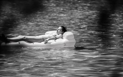 Woman lying on pool raft at sea