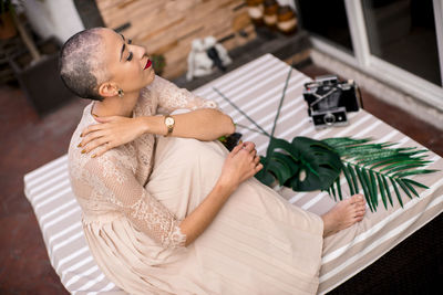 Side view of young woman sitting on table