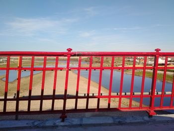 Railing on bridge against cloudy sky