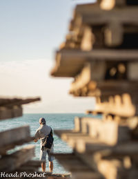 Rear view of man at sea shore against sky