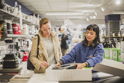 Saleswoman unboxing appliance for customer in store