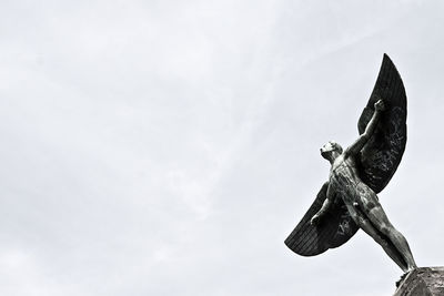 Winged human statue against clear sky