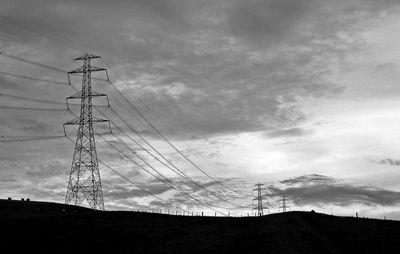 Low angle view of silhouette electricity pylon against sky during sunset