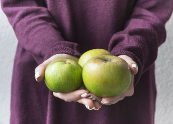 Midsection of woman holding green apples