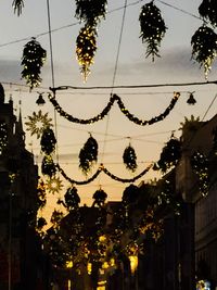 Low angle view of illuminated christmas tree against sky at dusk