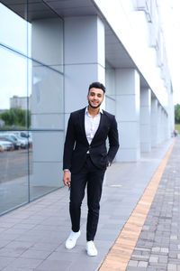 Young businessman standing against building