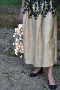 Low section of woman standing with birdcage on ground 