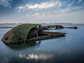 Abandoned boat on sea against sky