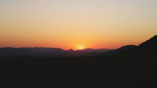 Scenic view of silhouette mountains against orange sky