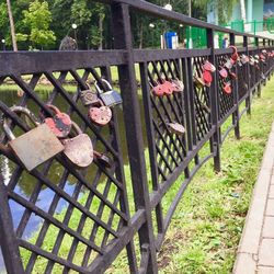 Padlocks hanging on railing by fence