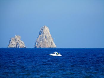 Sailboat in sea against clear blue sky