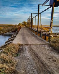 Walkway leading towards sea against sky