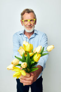 Close-up of young man holding flower against white background