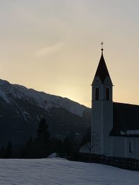 Church by building against sky during sunset