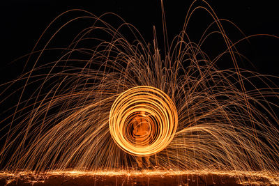 Low angle view of illuminated wire wools against sky at night