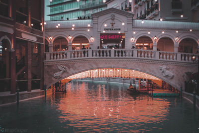 Arch bridge over river in city at night