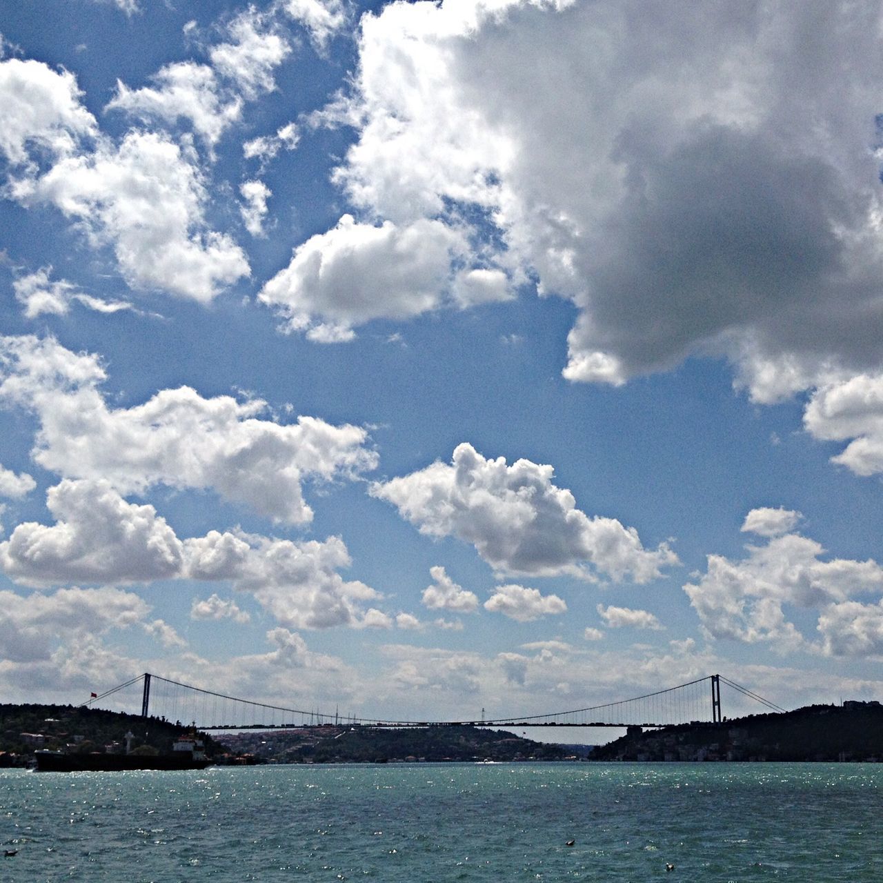 water, waterfront, sky, sea, cloud - sky, connection, cloud, transportation, cloudy, tranquility, tranquil scene, river, nature, rippled, scenics, built structure, beauty in nature, nautical vessel, day, outdoors