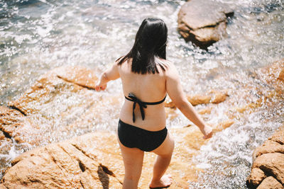 Rear view of young woman standing in water