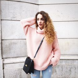 Thoughtful beautiful woman standing against wall