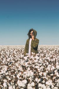 Full length of man sitting on pebbles against clear sky