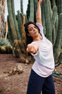 Latina girl with boho shirt dancing surrounded by cactus'