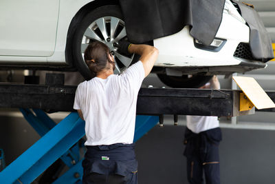 Rear view of man working at garage