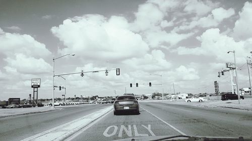 Cars on road against cloudy sky