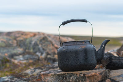 Teapot on stone against sky