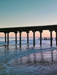 Pier over sea against clear sky during sunset