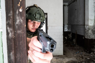 Soldier aiming gun while standing at abandoned building