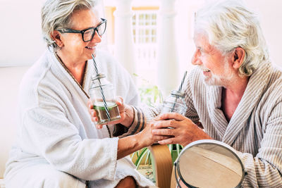 Senior couple in bathrobes enjoying drinks at hotel